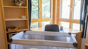 A room with a crib, wooden shelves, a desk, and large windows. - Via Radiras - Laax | Flims | Lake Cauma | Hiking (Laax)