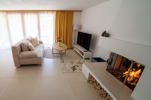 Ein modernes Wohnzimmer mit einer Couch, einem Couchtisch, einem Flachbildfernseher und einem Kamin.
