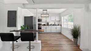 Eine moderne Küche mit weißen Schränken, einer Holz Arbeitsplatte und einem schwarzen Kühlschrank.