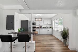 Eine moderne Küche mit weißen Schränken, einer Holz Arbeitsplatte und einem schwarzen Kühlschrank.