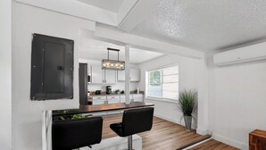 Eine moderne Küche mit Bar, weißen Wänden und Holzboden.