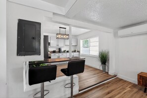 Eine moderne Küche mit Bar, weißen Wänden und Holzboden.