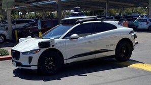 Un véhicule autonome blanc de la marque Jaguar Waymo est garé dans un parking couvert.