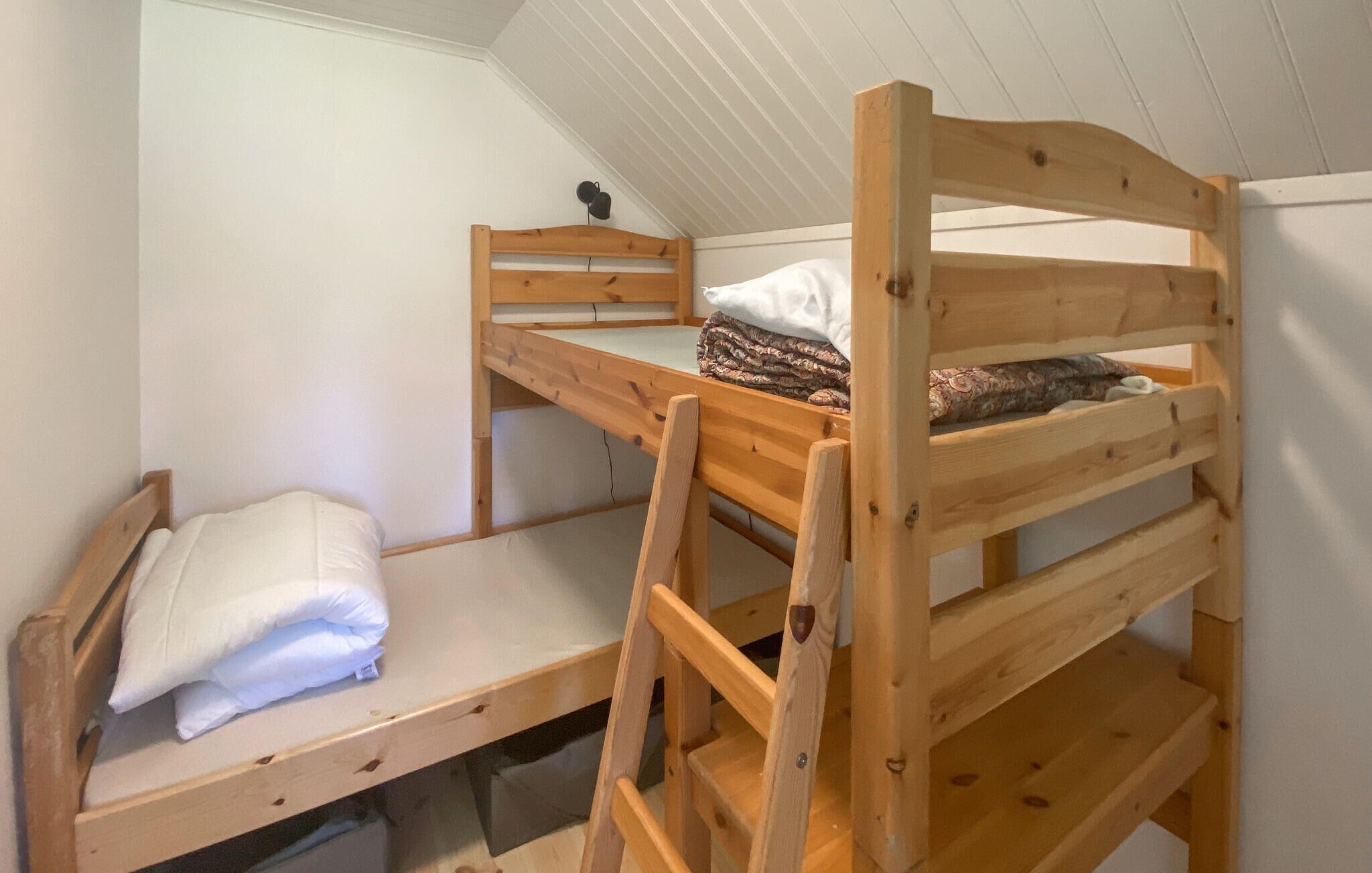 A bunk bed with a ladder, a small table, and a hanging object.