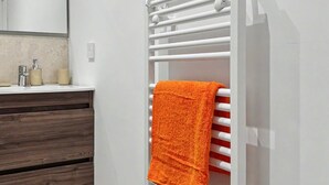 A bathroom with a white towel rack, a mirror, a wooden vanity, and a beige rug.