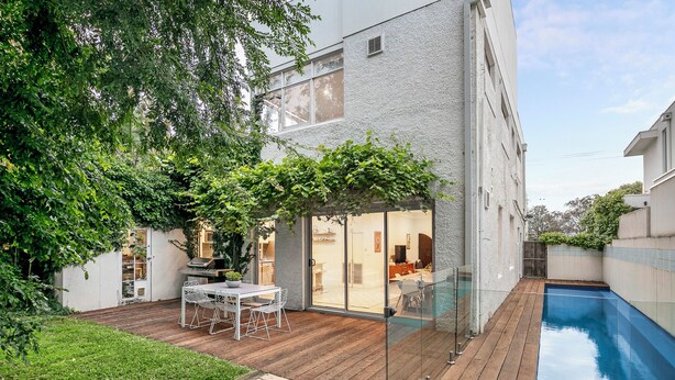 A modern house with a pool, a patio with a table and chairs, and a glass door leading to a living area. - Ultralux 5BDR Beachfront Home in Elwood (Elwood)
