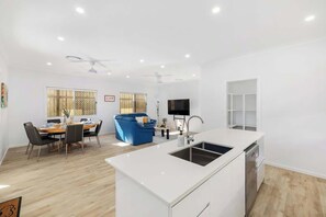 Eine moderne Küche mit weißer Arbeitsplatte, integriertem Spülbecken und einem Essbereich mit blauem Sofa und Esstisch.