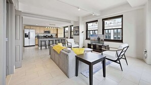 Una cocina moderna con una isla central, una zona de comedor con mesa y sillas, y un salón con sofá y televisor.