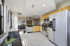 Eine moderne Küche mit Kühlschrank, Herd und Mikrowelle. Ein Essbereich mit Tisch und Stühlen ist ebenfalls vorhanden.