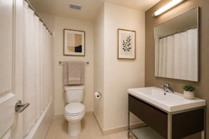 Ein Badezimmer mit Toilette, Waschbecken, Spiegel und Duschvorhang.