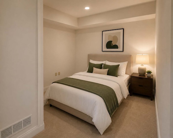 A bedroom with a bed, bedside table, lamp, and a framed picture on the wall. - Stylish High-Rise Loft in Downtown Detroit | City Views (Detroit)