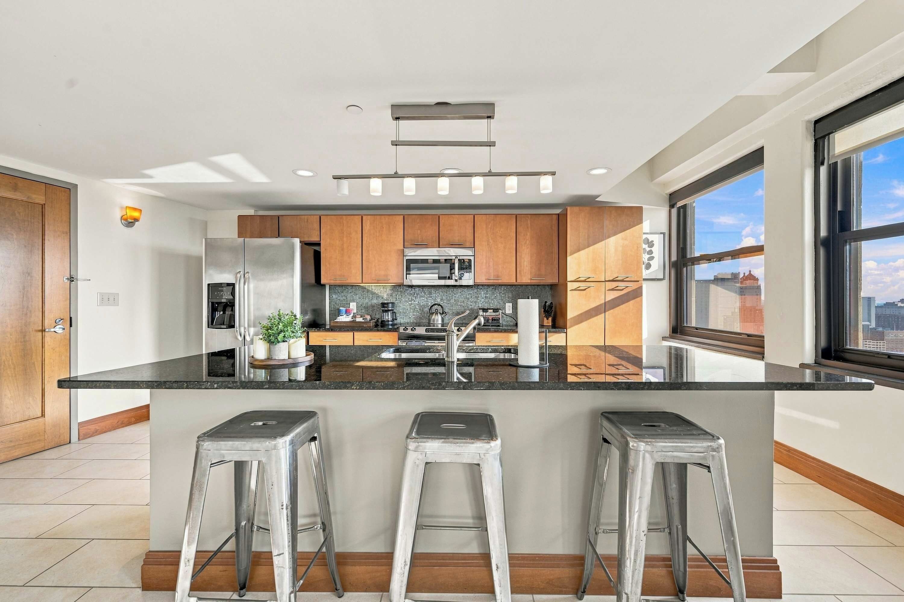 A modern kitchen with a central island, stainless steel appliances, and wooden cabinets.