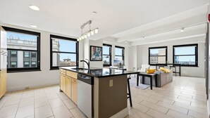 A modern kitchen with a central island, large windows, and a view of the cityscape. - Urban Loft Living in Downtown Detroit & Gym (Detroit)