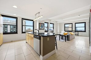 A modern kitchen with a central island, large windows, and a view of the cityscape. - Urban Loft Living in Downtown Detroit & Gym (Detroit)