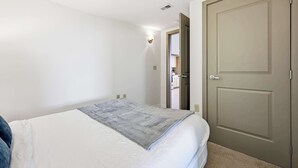 A bedroom with a bed, a door, and a hallway leading to a bathroom. - Urban Loft Living in Downtown Detroit & Gym (Detroit)