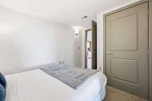 A bedroom with a bed, a door, and a hallway leading to a bathroom. - Urban Loft Living in Downtown Detroit & Gym (Detroit)