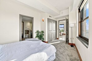 Quarto de hotel com cama, planta, banheiro e vista para o exterior.