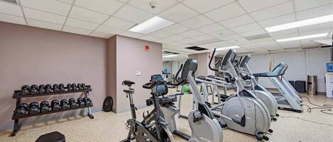 A gym with exercise equipment including dumbbells, a stationary bike, and treadmills.