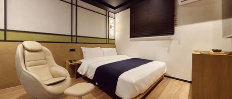 Una habitación de hotel con cama, una silla, mesita de noche y aire acondicionado.