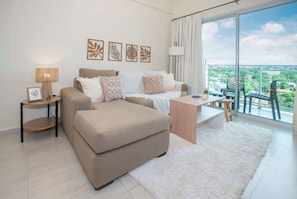 A modern living room with a sofa, a coffee table, a lamp, and a view of the city through large windows. - Corporate Stays Agora Villa Morra (Asunción)