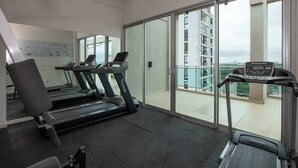 Een sportschool met loopbanden, een hometrainer en een roeimachine.