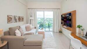Een moderne woonkamer met een bank, een salontafel, een tv-meubel en een balkon met uitzicht.
