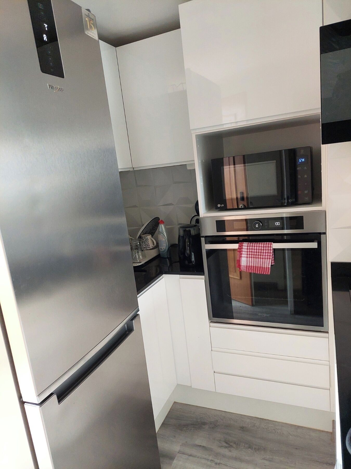 A modern kitchen with a stainless steel refrigerator, an LG microwave, and an oven.