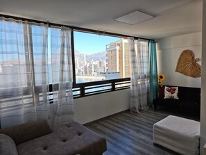 A room with a large window, a sofa, a small table, and a decorative wall piece. - Modern Pool&Sea View Apartment Benidorm (Benidorm)