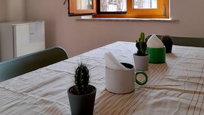 A room with a window, a bed, a chair, and several potted plants.