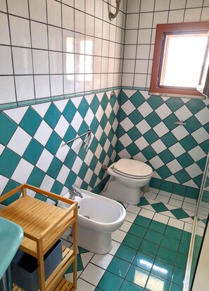 Un baño con suelo de baldosas a cuadros, un inodoro, un lavamanos y un armario de madera.