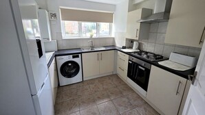 A compact kitchen with a washing machine, a stove, and a sink. - Modern 2BDR Flat Near Stratford and Central London (Greater London)