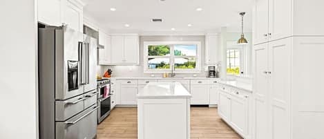 A modern kitchen with white cabinetry, stainless steel appliances, and a large island.