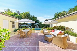 Eine Terrasse mit Esstisch, Stühlen und einem Pool.