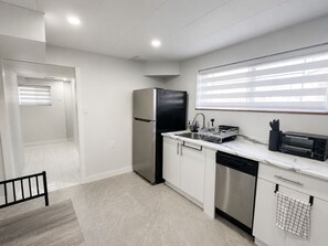 A modern kitchen with a stainless steel refrigerator, a dishwasher, a sink with a dish rack, and a built-in oven. - Newly renovated private basement Suite - central hub (Vancouver)