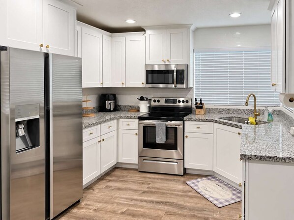 A modern kitchen with stainless steel appliances, white cabinetry, and a granite countertop. - Chandler 4BR | Private Pool | Pet Friendly (Chandler)