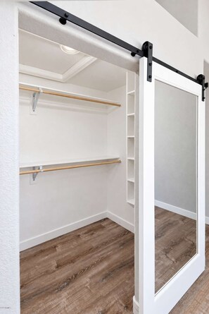 Une pièce dotée d’une porte coulissante, d’un plancher en bois et de murs blancs.
