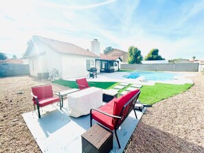 Eine Außenpatio mit Pool, einer überdachten Sitzgelegenheit und einem Rasen.