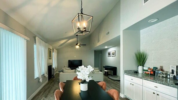 Un salon moderne avec une table à manger noire, un canapé blanc et un téléviseur en arrière-plan.