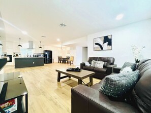 Ein modernes Wohnzimmer mit einer Couch, einem Couchtisch und einem Essbereich mit Stühlen und einem Tisch.