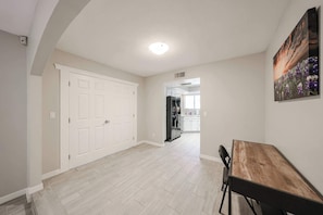 Un pasillo amplio con comedor, puertas blancas y una cocina al fondo.
