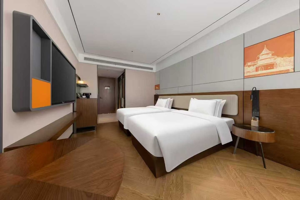 A hotel room with a large bed, a desk, a flat-screen TV, and a painting on the wall.