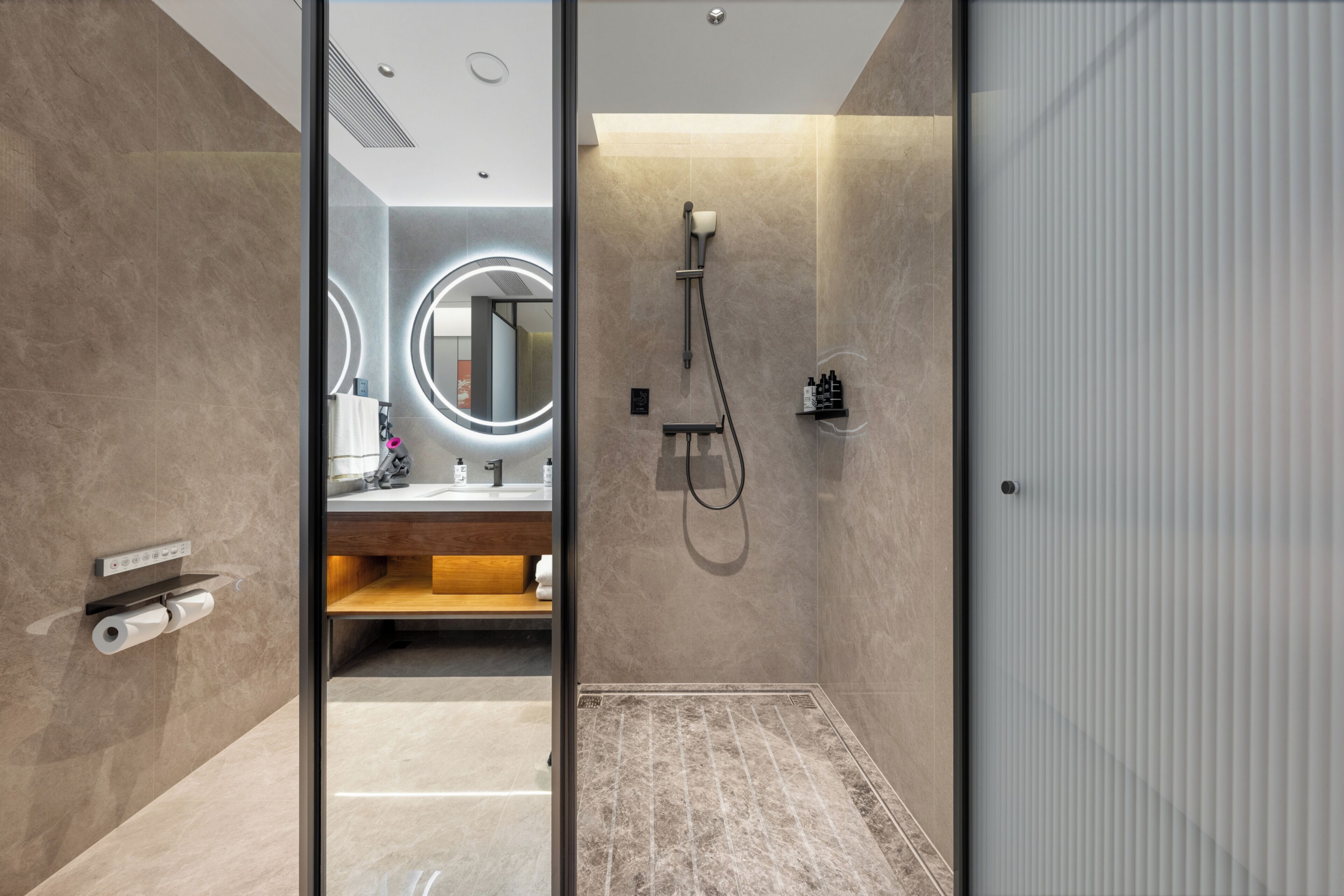 A modern bathroom with a glass door, a shower, a vanity with a mirror, and a towel rack.