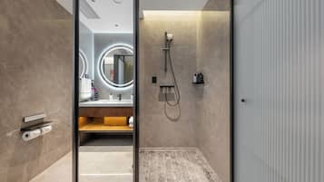 A modern bathroom with a glass door, a shower, a vanity with a mirror, and a towel rack.
