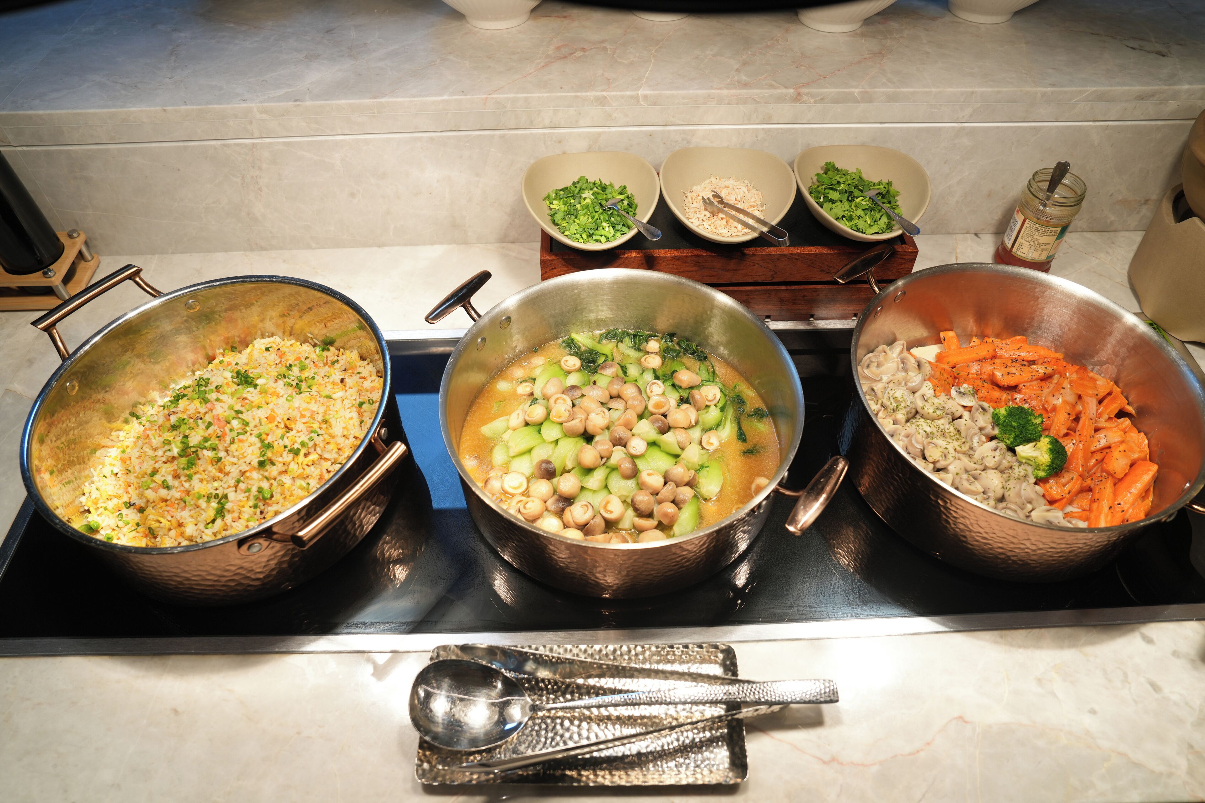 A kitchen with three pots on the stove, each containing different food items.