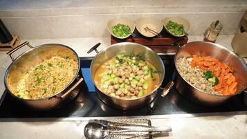 A kitchen with three pots on the stove, each containing different food items.