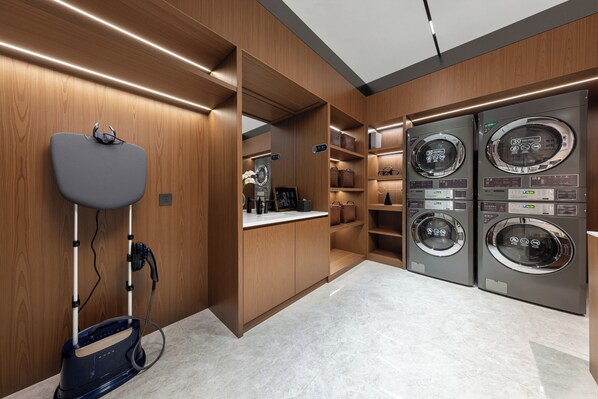 A laundry room with two washing machines, a sink, and a mirror.