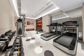Et moderne fitnesscenter med løbebånd, håndvægte og træningsmaskine.