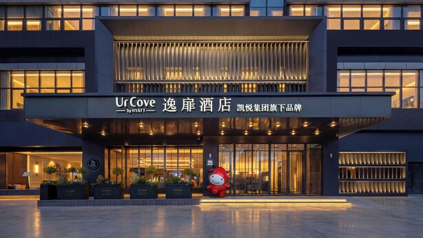 A modern hotel entrance with a large sign, potted plants, and a mascot. - UrCove Yangzhou China Grand Canal Museum (Yangzhou)