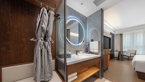 A modern hotel bathroom with a wooden vanity, a large mirror with lights, a bathtub, and a separate shower area. - UrCove Yangzhou China Grand Canal Museum (Yangzhou)