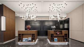 Una moderna zona de recepción con mostradores de madera, un mostrador negro y un techo con luces colgantes.